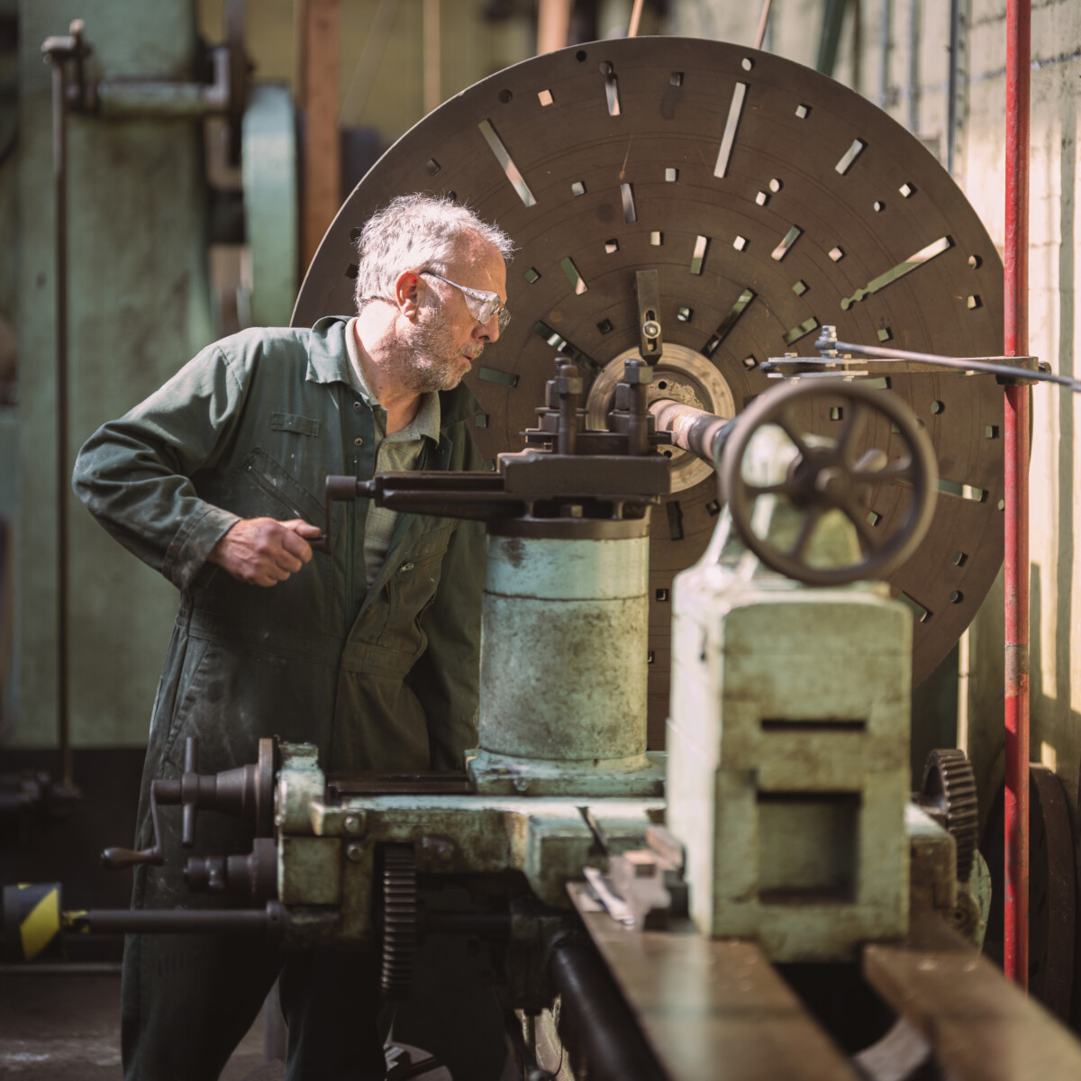 Volunteer in green boiler suit working with a lathe